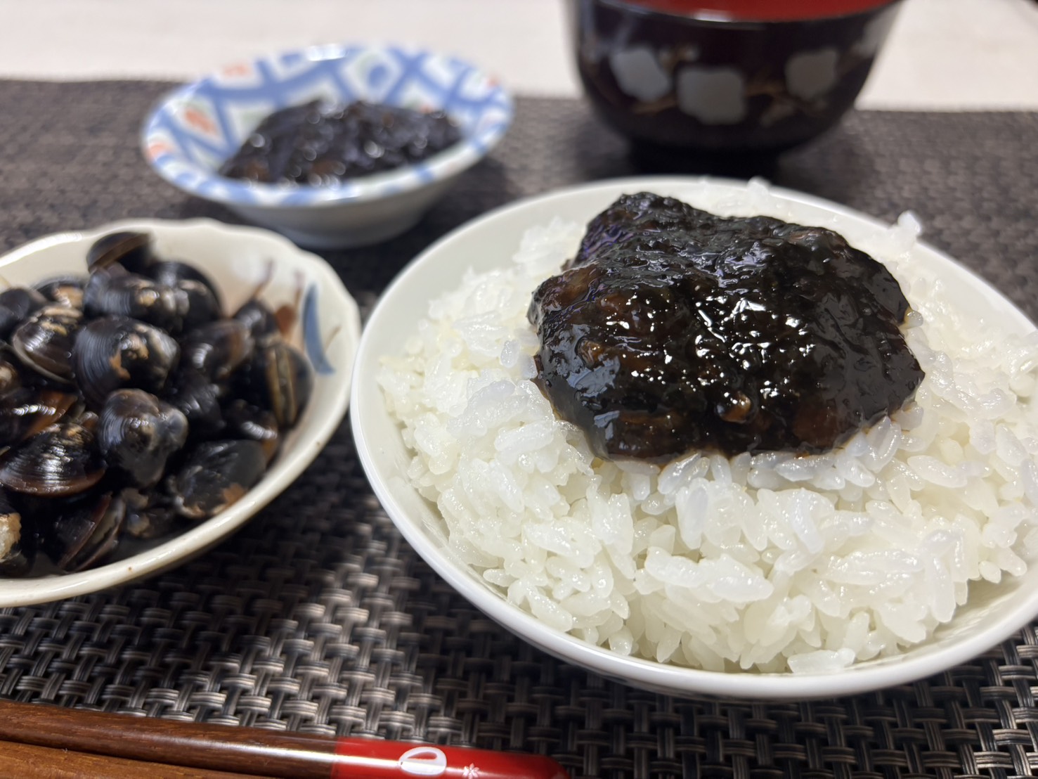 炊きたての白いご飯に乗せたしじみ入りのり佃煮と、傍らに添えられた新鮮な宍道湖産しじみのイメージ写真。素材の良さと食欲をそそる盛り付け。