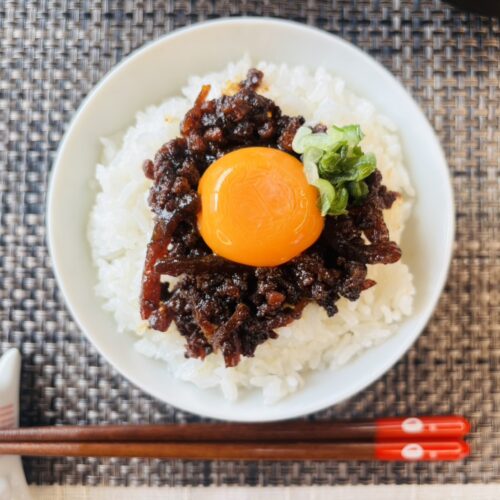 炊きたてのご飯に「しまねの和牛しぐれ煮」と生卵をトッピングした贅沢な卵かけご飯（TKG）。とろける卵黄と和牛の旨味が絡み合うシズル感のある写真。