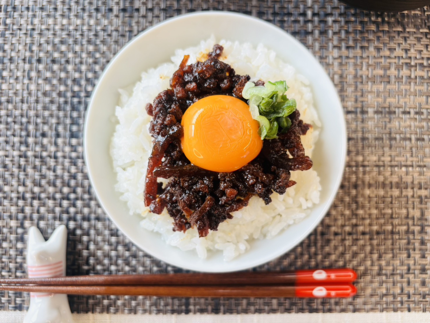 炊きたてのご飯に「しまねの和牛しぐれ煮」と生卵をトッピングした贅沢な卵かけご飯(TKG)。とろける卵黄と和牛の旨味が絡み合うシズル感のある写真。