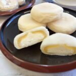 半分にカットされた大山ヨーグルトクリーム大福の断面。中心のホイップクリームとヨーグルト餡、外側のお餅が織りなす「とろりと美味しそうな三層構造」のアップ写真。